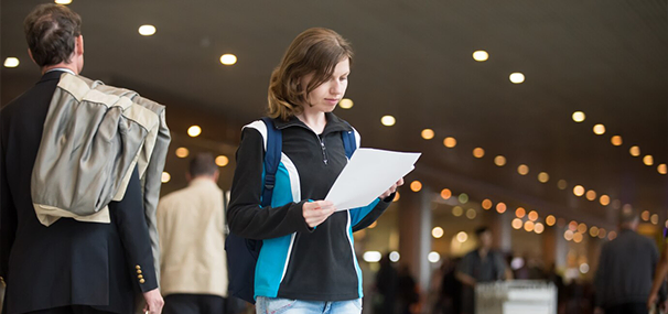 Young woman reading travel documents at airport for Abroad Study Consultancy Kerala